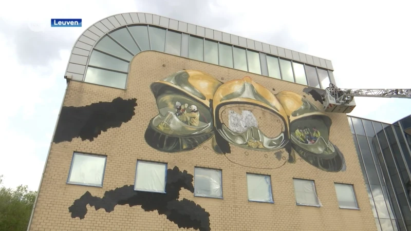Brandweerman maakt muurschildering op gevel brandweerkazerne Leuven
